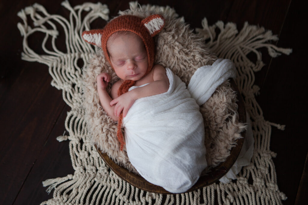 Newborn baby wrapped, with a hat that has fox ears