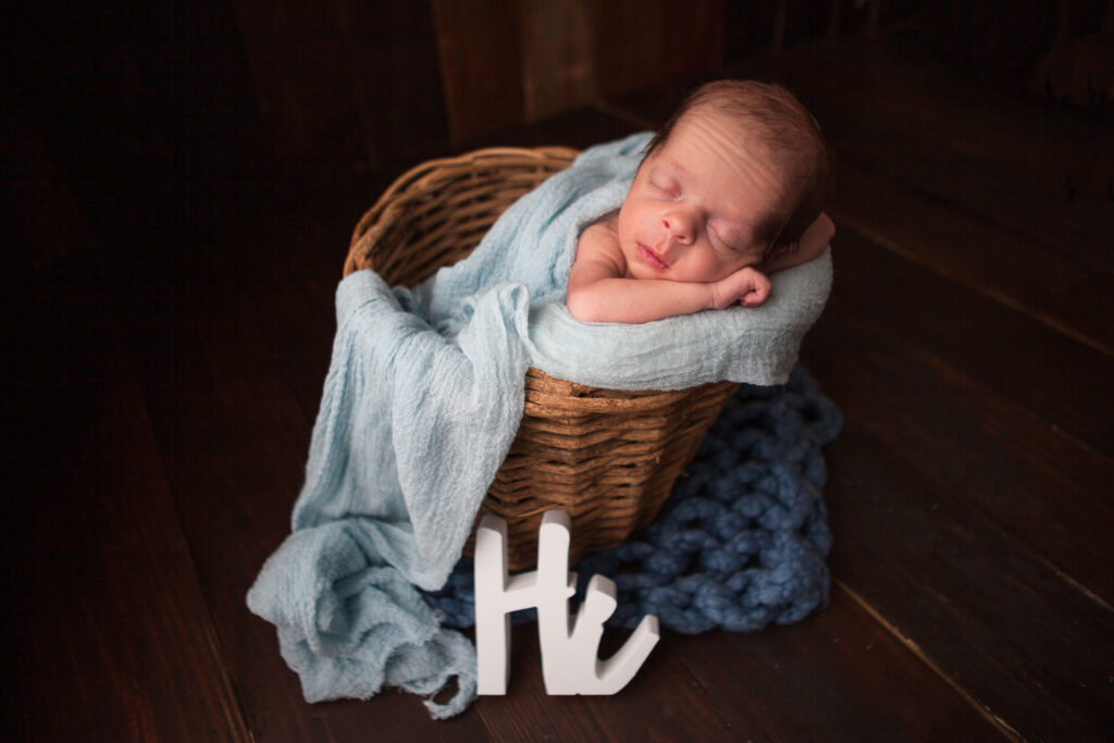 A picture of a newborn baby in a basket with the word "Hi" right below the basket