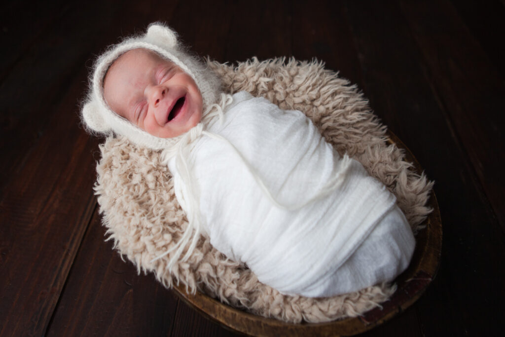 Shot of newborn baby smiling while wrapped in white
